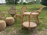 several wicker chairs and tables in a grassy field with trees in the background
