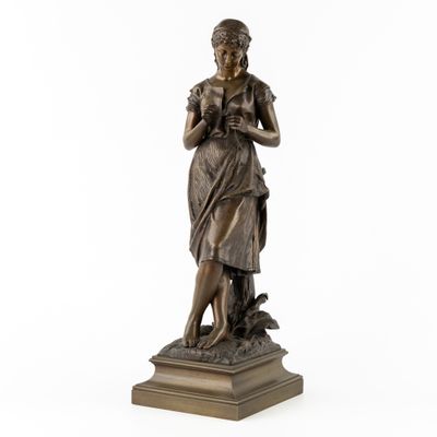 une statue en bronze d'une femme tenant un oiseau sur un piédestal