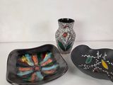 three pieces of art glass sitting on a table next to a vase