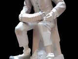 a statue of a man sitting on a stool holding a book