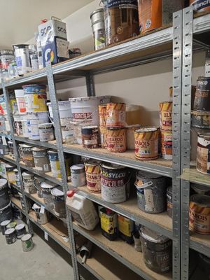 des étagères remplies de différentes sortes de peinture et d'autres articles dans une pièce