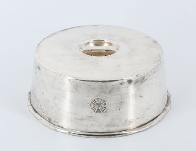 a silver plate with a domed lid on a white surface