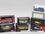 quatre modèles différents de voitures dans des boîtes, posés sur une surface blanche