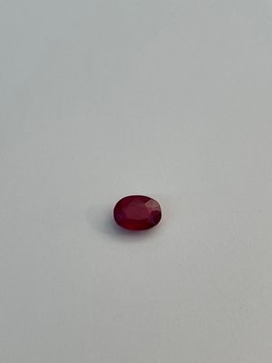 an oval shaped red stone on a white surface