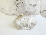 a sculpture of a head on a rock on a white surface