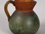 a brown and green vase sitting on a white surface