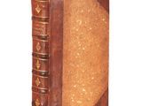 an old book with a brown cover sitting on top of a white surface