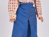 une poupée aux cheveux blonds, portant un pantalon bleu et des bottes rouges