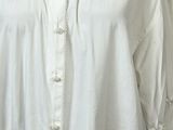 the shirt is white and has a lace trim around the collar