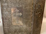 an old silver book with a cross on it sitting on a table