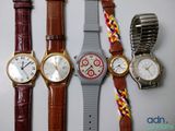 several watches are lined up on a table with a watch band