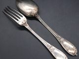 two silver spoons and a fork on a black surface