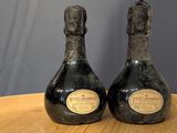 two bottles of wine sitting on top of a wooden table next to each other