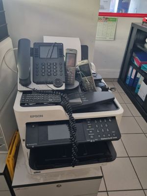 une pile de téléphones et une imprimante dans une pièce