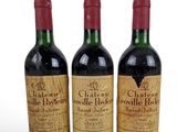 three bottles of red wine sitting next to each other on a white surface
