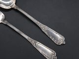two silver spoons and a spoon on a black surface