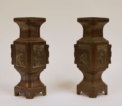 deux vases marron ornés de motifs sur un fond blanc