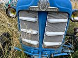 un tracteur bleu qui est garé dans l'herbe