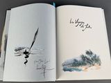 an open book with a drawing of a sailboat in the water