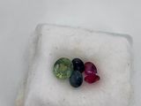 a close up of three different colored gems on a white surface