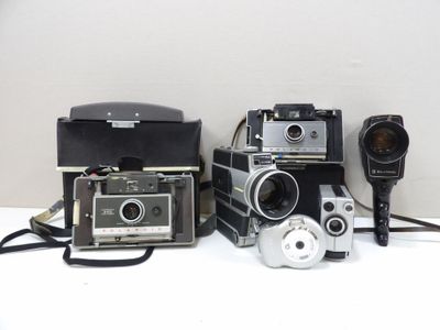 several old cameras are lined up on a white surface