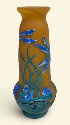 un vase sur lequel sont peintes des fleurs bleues sur fond blanc