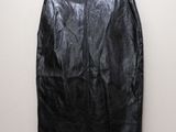 a black leather skirt hanging on a hanger against a wall