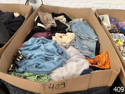 une boîte en carton pleine de vêtements posée sur le sol