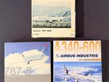 trois livres posés sur une table, avec un avion en arrière-plan