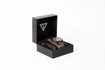 la montre se trouve dans un coffret noir posé sur une surface blanche