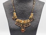 un collier avec un mannequin noir orné de perles dorées et marron