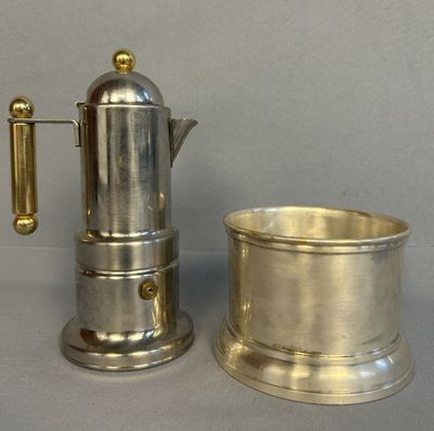 une cafetière en argent et une tasse en argent posées sur une table