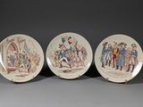 three plates with a painting of people on them sitting on a table