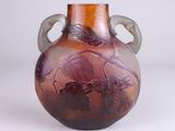 a purple vase with leaves on it sitting on a white surface