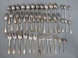 a lot of silver spoons and forks laid out on a table
