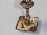 a small candle holder and a small plate on a table