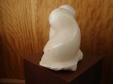 a white sculpture of a bear sitting on top of a wooden stand