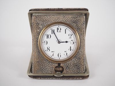 a small silver clock sitting on top of a white table