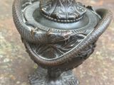 une statue représentant un serpent au sommet d'un vase