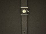 un gros plan sur un sac noir orné d'une montre argentée