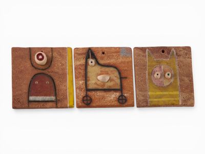 trois aimants en bois arborant des motifs différents, posés sur une surface blanche