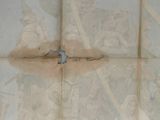 a tile floor with a cross on it and a toilet in the corner