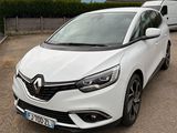 La voiture blanche est garée sur le parking, à côté d'une camionnette.