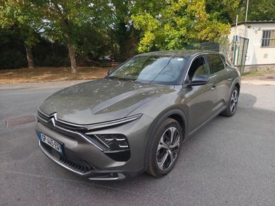une voiture grise garée sur le bord de la route, devant une maison