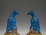 pair of blue parrots sitting on top of a golden stand