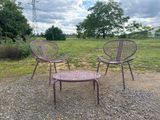 two chairs and a table in a field with trees in the background