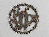 an old iron tsuba with a bird and flowers in the center