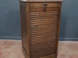 une vieille armoire en bois surmontée de volets, dans une pièce
