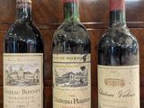 three bottles of wine are lined up on a red cloth