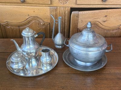 a silver tea set on a wooden table next to a dresser